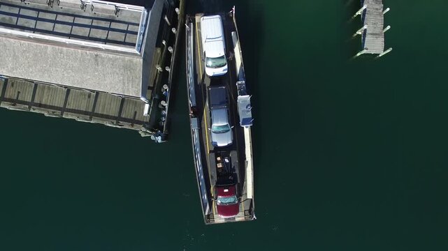 Aerial view of a Chappaquiddick Ferry carrying cars between docks, surrounded by the dark green water, creating a stark contrast, Edgartown, Massachusetts, United States.