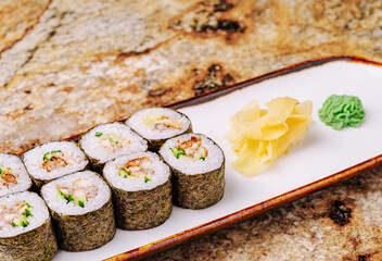 Fresh sushi rolls served on a white plate with wasabi and ginger