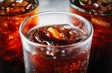 Cola soft drink with ice cubes, soda fizzy drink in Cold three glass on gray background, close-up