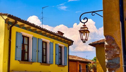 Bellagio, Lake Como, Italy. Ancient streets of old town. Vibrant houses with windows and street lamp at narrow Bright sunny summer evening during sunset..