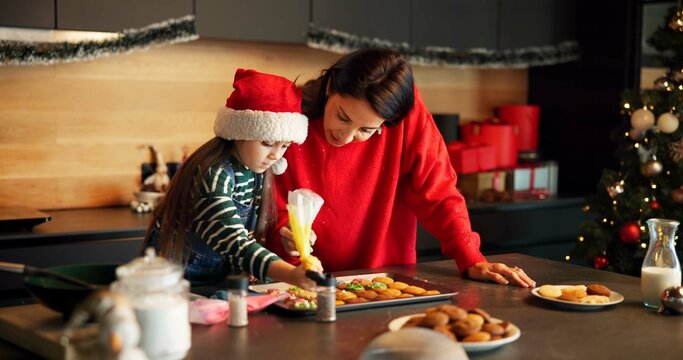 Christmas, mother or child in kitchen with icing, baking help and bonding together in holiday season. Festive, learning or family in house with cookie, connection or sweet treat frosting for Santa. - Powered by Adobe