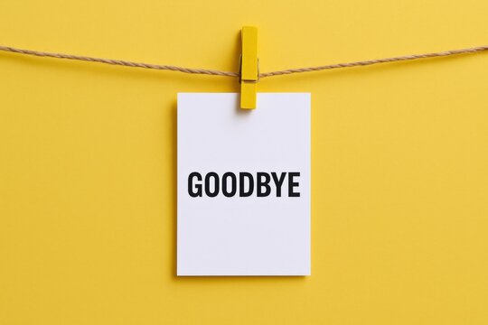 Goodbye message pinned on yellow background. Farewell concept with white card and wooden clip for design