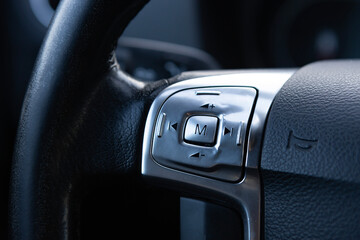 Close-up view of a car steering wheel control panel with buttons for navigation and settings