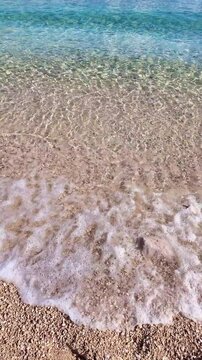 Tranquil waves gently lapping pebble beach under clear blue sky