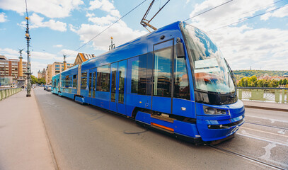 Naklejka premium Modern blue tram on Prague city bridge.