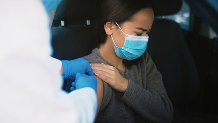 Patient, pain and hands with vaccine, car and healthcare for Covid 19 prevention, help and treatment. Drive thru, doctor and injection for RSV immunization, sore and booster for woman in vehicle