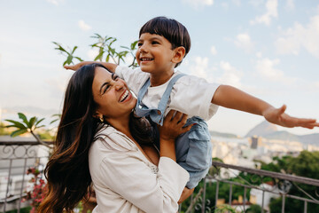 Mother and son playing airplane game on a sunny terrace