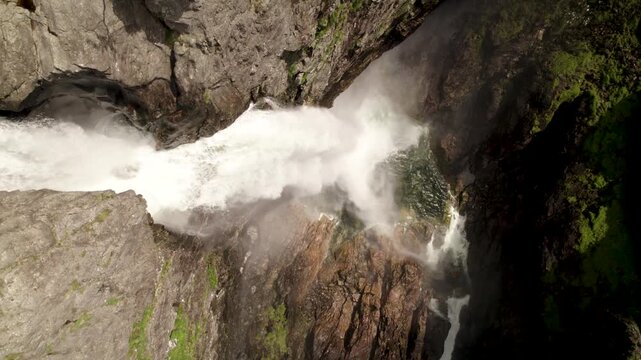 Aerial view of water cascading powerfully down a steep cliff face, carving through rugged rocks, Dirdal, Rogaland, Norway.