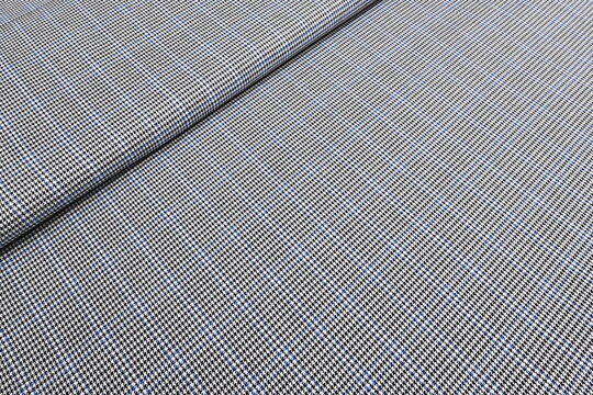 Striking black and white houndstooth fabric with a bold blue overcheck. Classic suiting wool textile ideal for contemporary tailored suits, jackets and sophisticated fashion statements. 