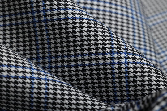 Striking black and white houndstooth fabric with a bold blue overcheck. Classic suiting wool textile ideal for contemporary tailored suits, jackets and sophisticated fashion statements. 