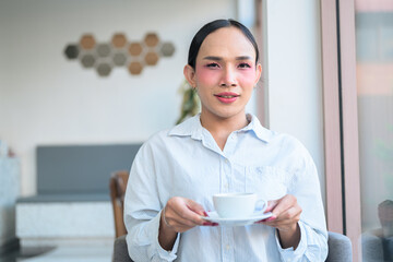 Portrait of a young Thai transgender business person at cafe restaurant holding coffee cup