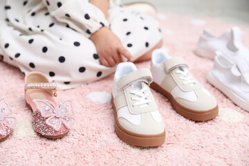 Little girl choosing between different shoes at shop, closeup