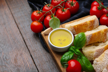Tasty baguette served with oil, tomatoes and basil on wooden table, closeup. Space for text