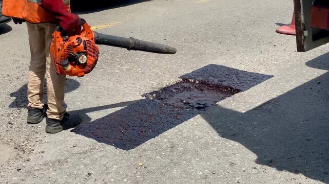 construction worker blowing and preparing for potholes fising at the highway