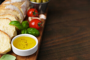 Tasty baguette served with oil, tomatoes and basil on wooden table, closeup. Space for text
