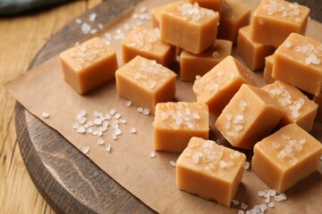 Tasty caramel candies with salt on wooden table, closeup