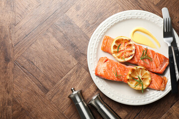 Salt pepper shakers and grilled salmon served on wooden table, flat lay. Space for text