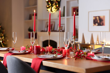 Stylish Christmas table setting with plates, glasses and burning candles in festive decorated room, closeup. Bokeh effect