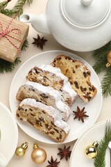 Slices of traditional Stollen, teapot and Christmas decor on white table, flat lay