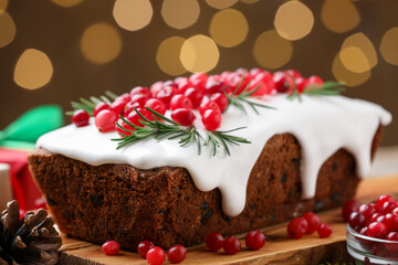 Tasty Christmas cake with cranberries and rosemary on table, closeup. Bokeh effect