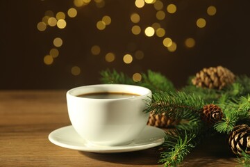 Aromatic coffee and Christmas decor on wooden table against blurred lights, closeup
