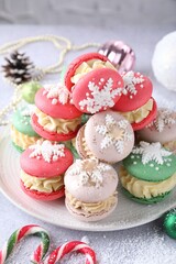 Tasty Christmas macarons and festive decor on light table, closeup