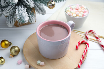 Tasty cocoa, marshmallows, candy canes and Christmas decor on white wooden table, closeup