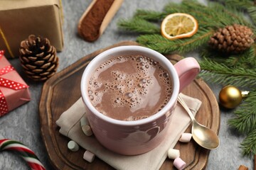 Tasty cocoa, marshmallows and Christmas decor on grey table, closeup