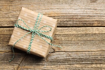 Naklejka premium Decorated Christmas gift on wooden background, top view. Space for text