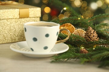 Aromatic coffee and Christmas decor on white wooden table against blurred lights, closeup