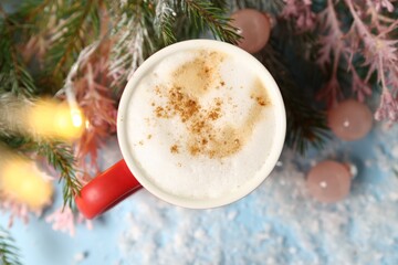 Aromatic coffee in cup and Christmas decor on light blue background, flat lay. Bokeh effect