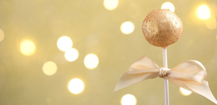 Tasty cake pop on beige background with blurred lights, closeup and space for text. Christmas treat