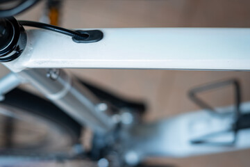 A macro shot focusing on the internal cable routing port on a clean, white bicycle top tube, highlighting the modern frame design and integration