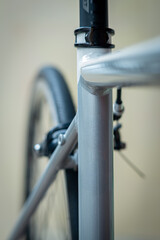 Close-up of a bicycle frame and rear wheel, showcasing clean metal tubing, smooth welds, and precise components with a soft, minimal background