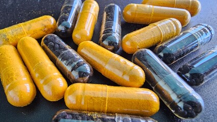 Colorful capsules filled with turmeric and black cumin demonstrate health supplements concept