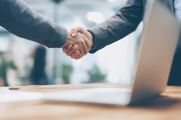 Two colleagues shaking hands across desk