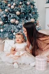 Family celebration with a little girl in a fancy dress beside a decorated Christmas tree and a...