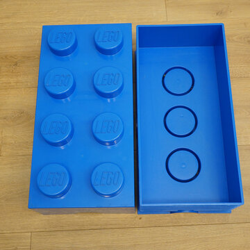 Large blue LEGO storage brick with lid open on a wooden surface