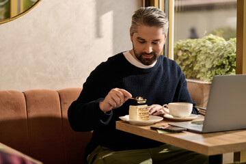 Mature man enjoys dessert while working in a stylish cafe during a sunny afternoon