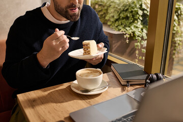 Mature man enjoying dessert and coffee while working in a cozy cafe setting