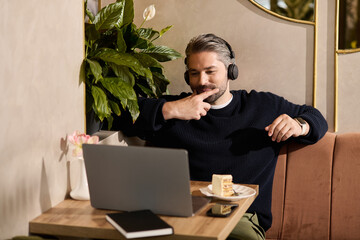 Mature handsome man enjoying dessert while working on a laptop in a stylish cafe