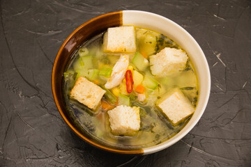 Vegetable soup with chili pepper and white bread croutons on a dark background