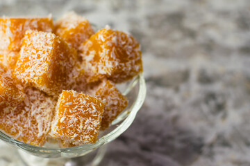 Sweet pumpkin dessert. Pumpkin and coconut marmalade in a transparent glass bowl on a light background