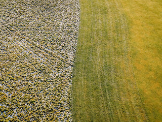 Aerial view of contrasting landscapes showcasing a snowy area transitioning into lush green grass, highlighting seasonal changes and the beauty of nature's cycles