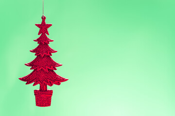 Sparkling red christmas tree ornament hanging against a soft green background