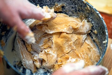 Kneading dense honey dough in a pot for making a traditional honey cake