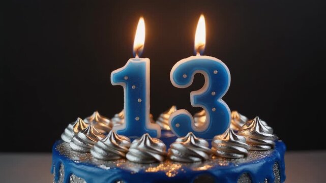 Happy 13th birthday concept with a blue decorated cake and lit number thirteen candles against a dark background for a party