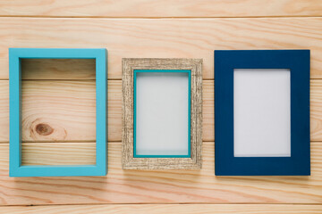 Three empty picture frames of varying sizes and styles arranged on a wooden background