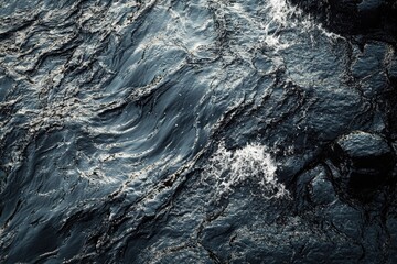 Dark, agitated water surface with ripples and splashes. Reflections create shimmering patterns, highlighting the dynamic flow and texture of the deep blue-green liquid.