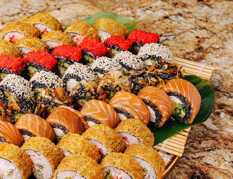 Sushi platter with assorted rolls served on a wooden tray at a festive gathering - Powered by Adobe
